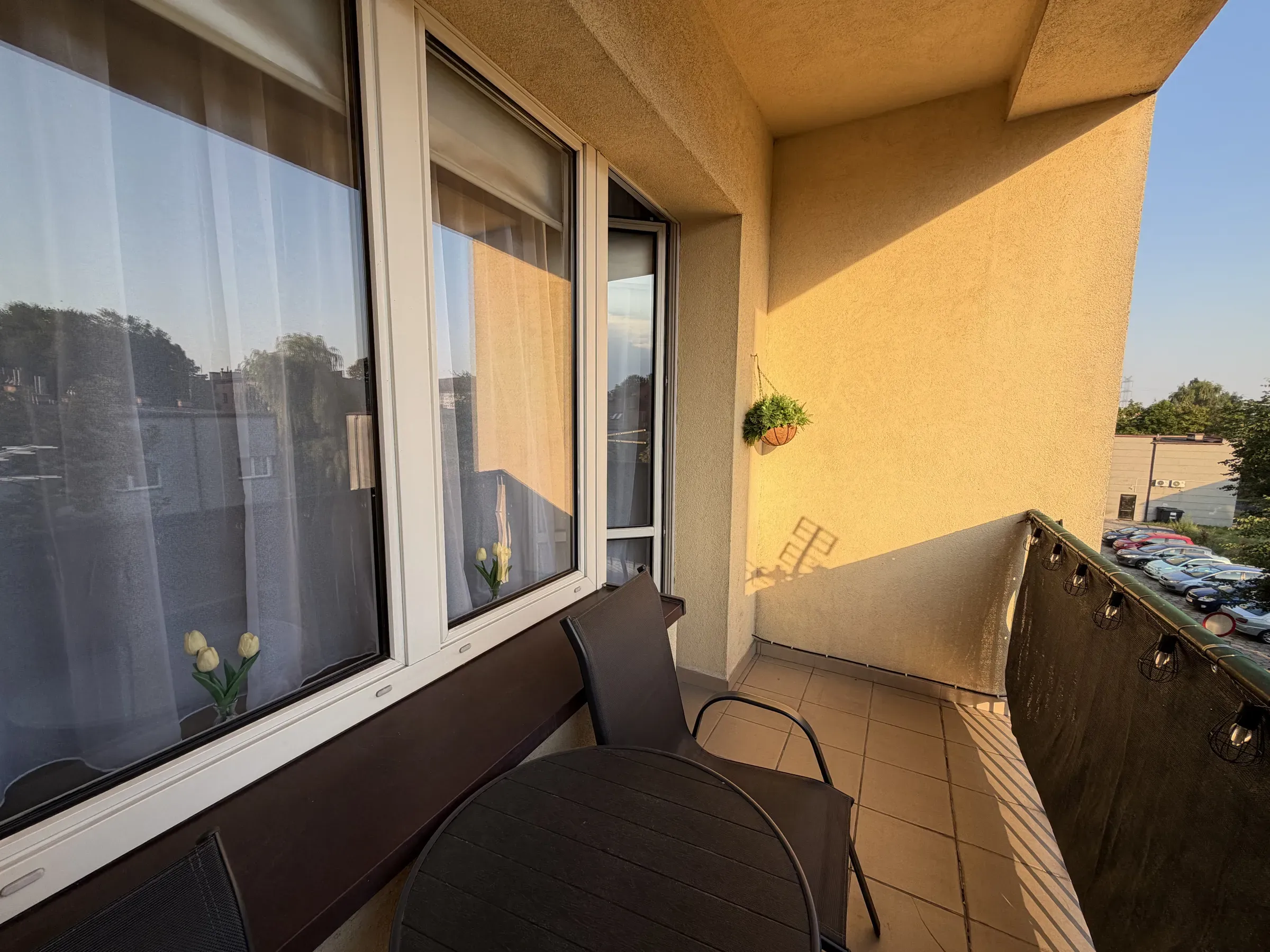 Balkon ze stolikiem i krzesłami, widok na zieleń dzielnicy Helenka w Zabrzu