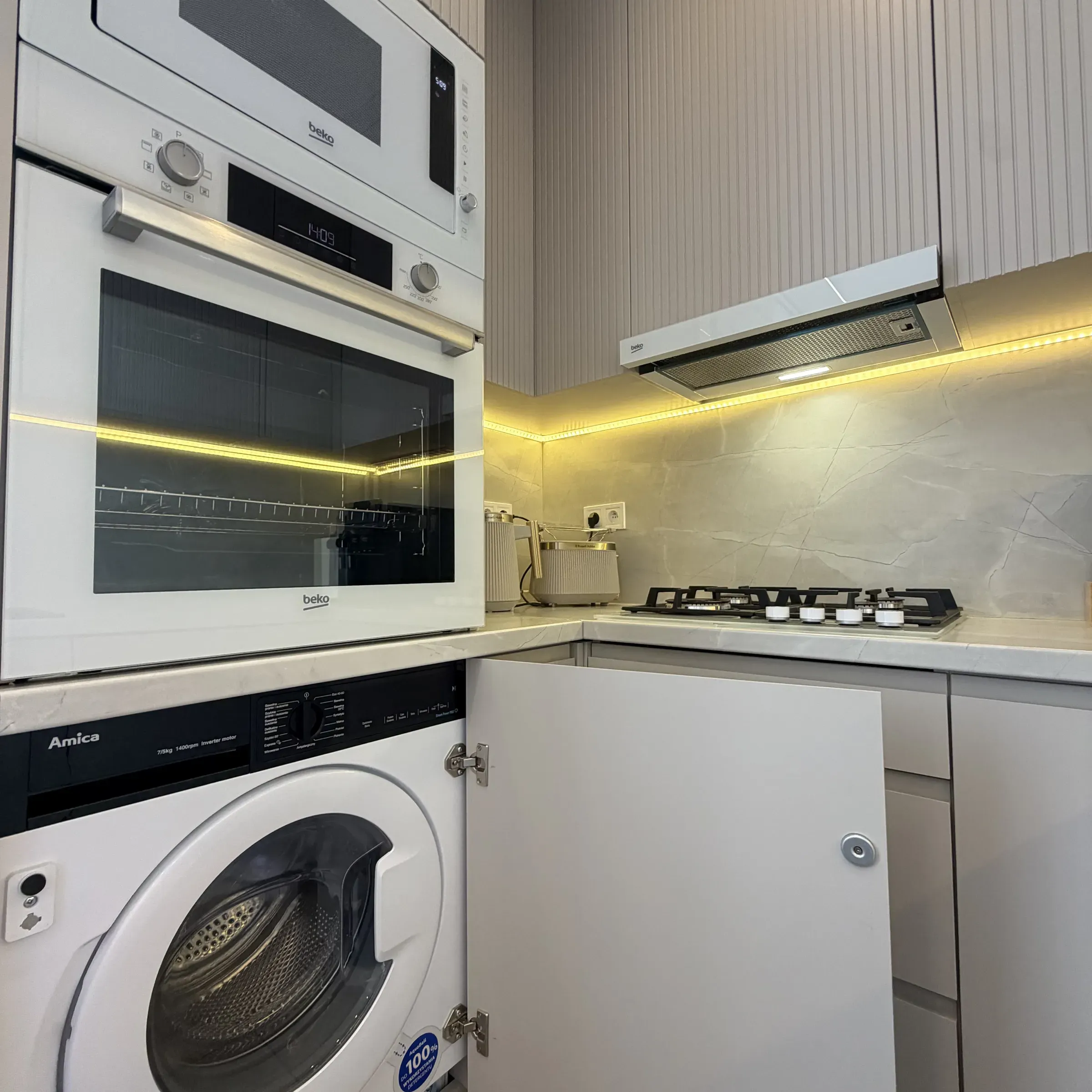 Pralka i piekarnik w zabudowie kuchni apartamentu