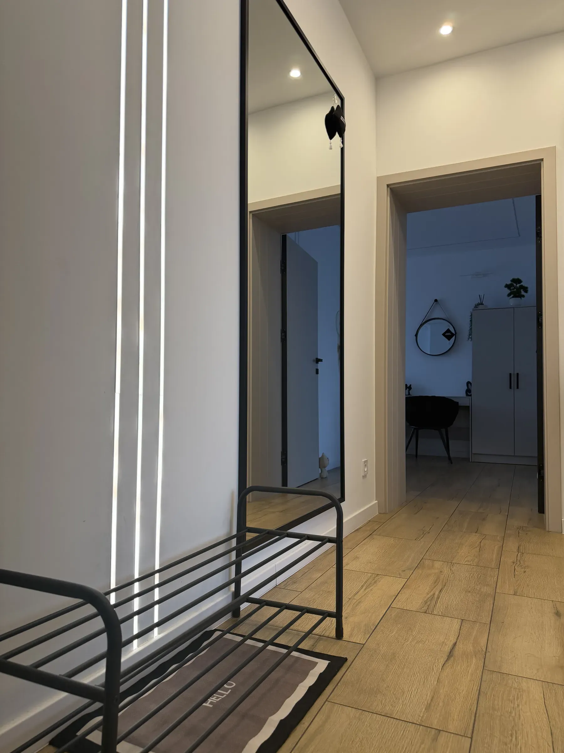 Szafka na buty i wysokie lustro przy wejściu do apartamentu